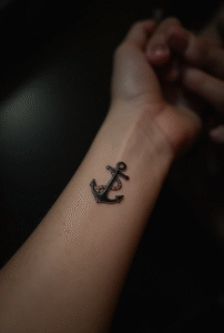 Simple anchor wrist tattoo for women representing strength and stability — minimalist black ink design with rope detail, timeless small tattoo.