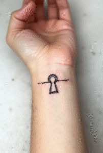 Tiny keyhole wrist tattoo for women symbolizing self-discovery and mystery — minimalist black ink design, meaningful small tattoo.