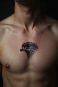 “Close-up of a tiny falcon eye tattoo on a male chest, designed with fine black lines and subtle shading for a sharp, focused look.”